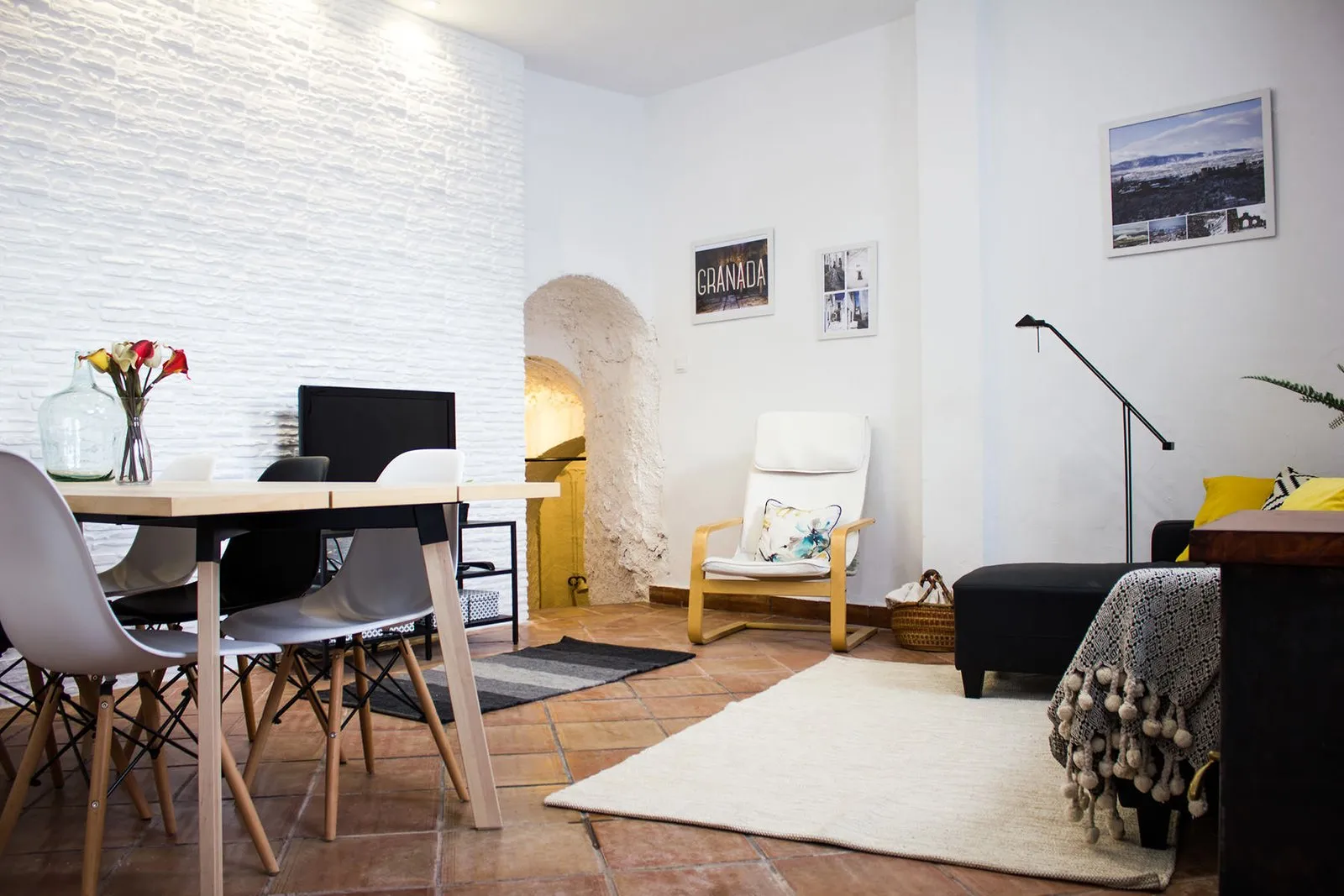 Living room with dining table, sofa and rug beneath whitewashed ceilings