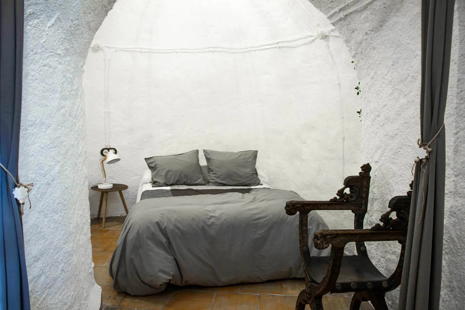 Main bedroom with a double bed and a carved wooden chair inside the cave