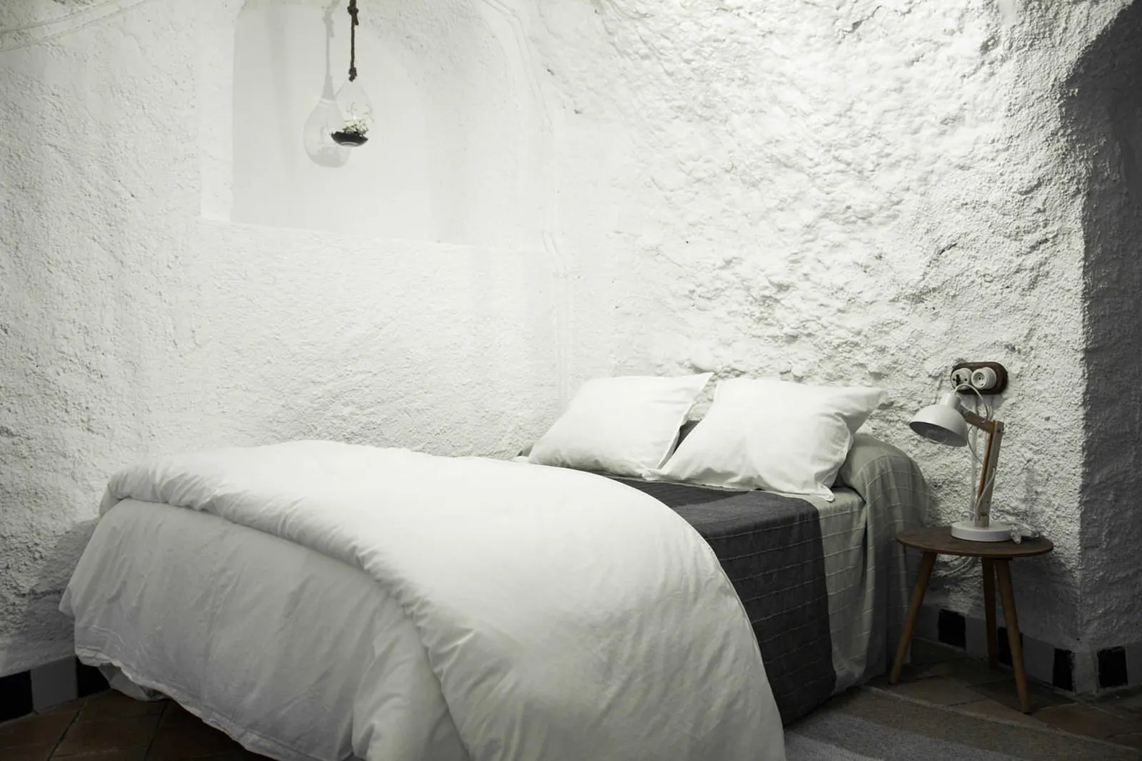 Large single bed with white linen against the cave wall