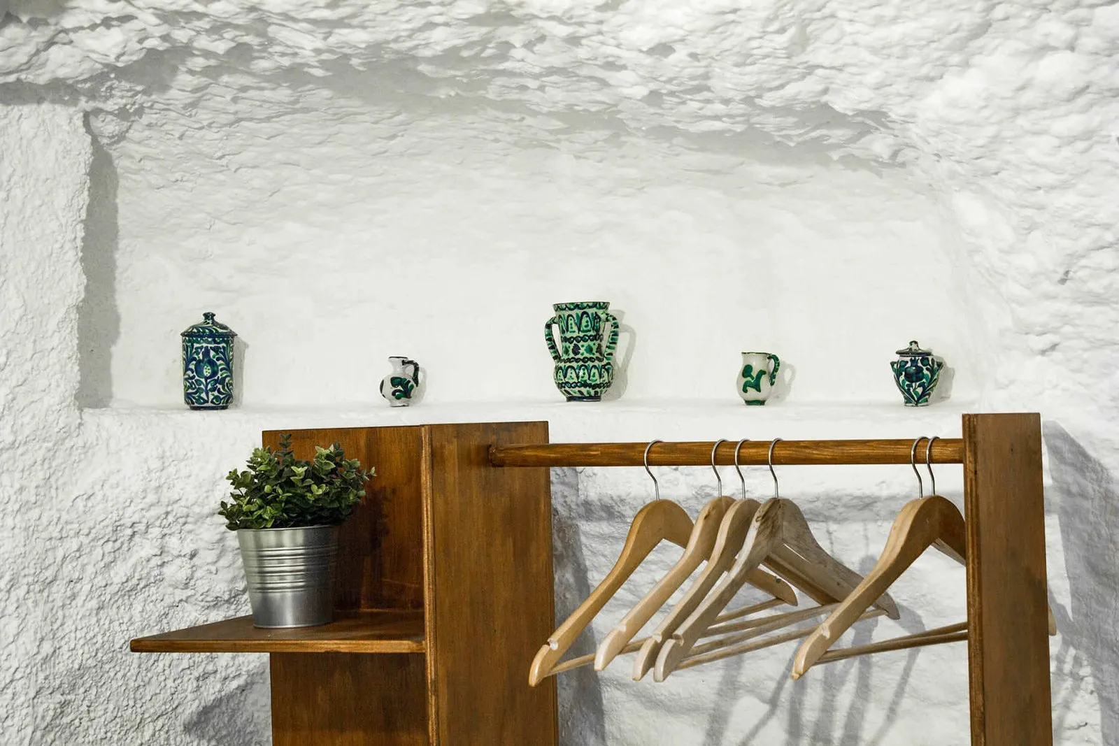 Wooden coat stand and shelf with towels next to the bed