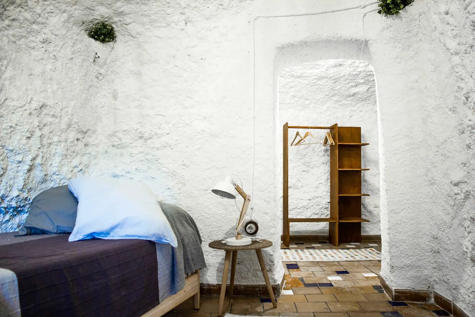 Bedroom with a single bed and a wooden shelf at the back